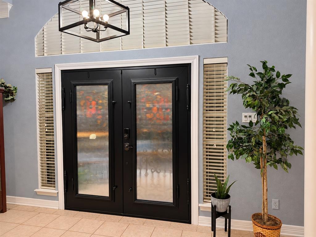 Double entry doors with glass panels, arched transom window, and matte black geometric pendant lighting