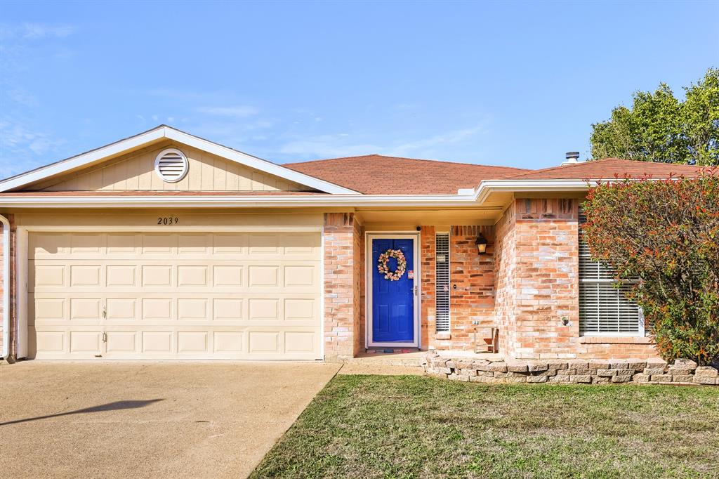 Single-story exterior featuring a brick and siding facade, attached two-car garage, recessed entryway, and stacked-stone garden border