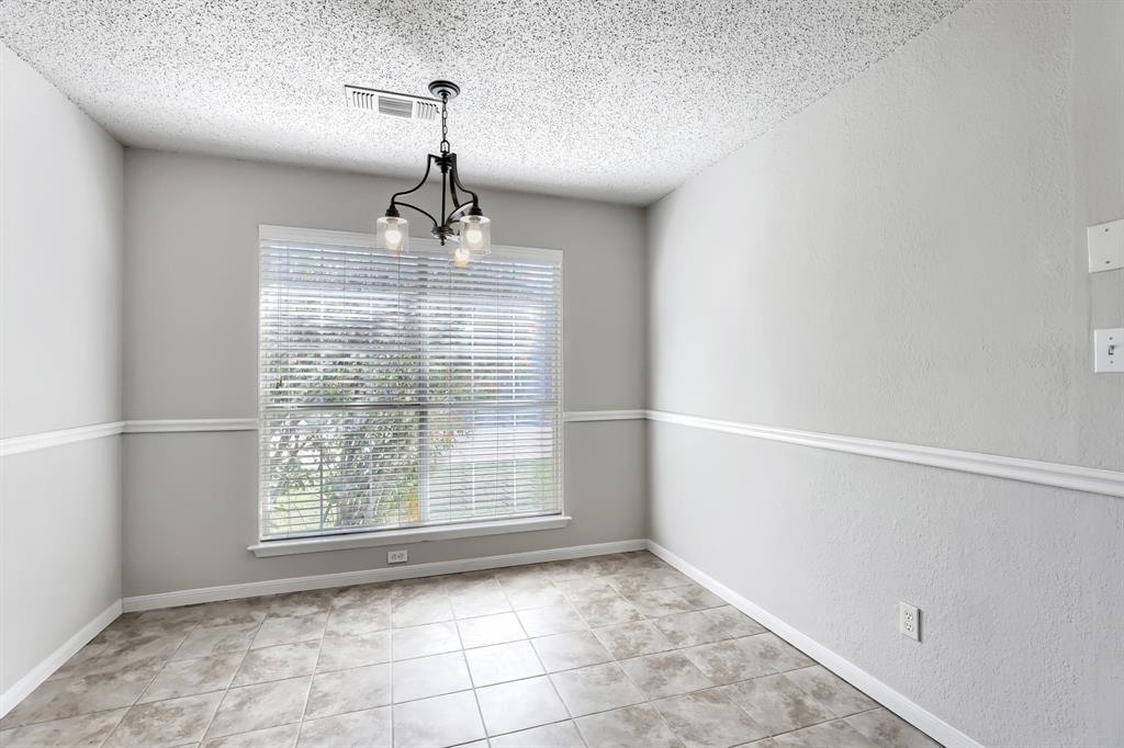 Neutral-toned interior space featuring light-colored tile flooring, chair rail molding, and a metal multi-light chandelier