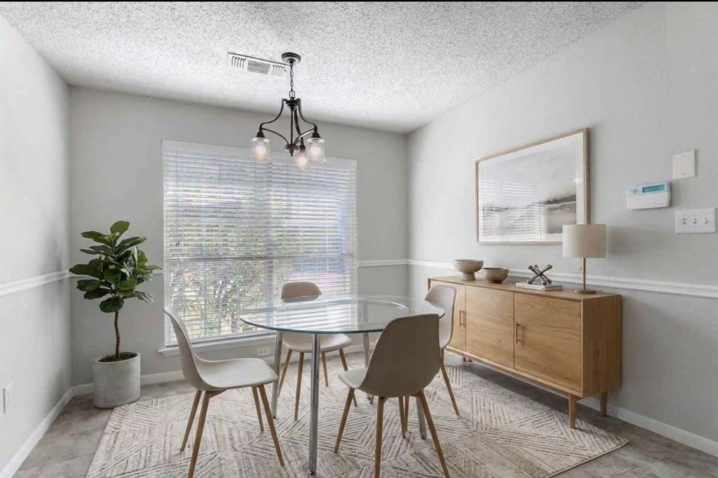 Virtually Staged - Multi-pane window with horizontal blinds, three-light metal chandelier, and white chair rail molding