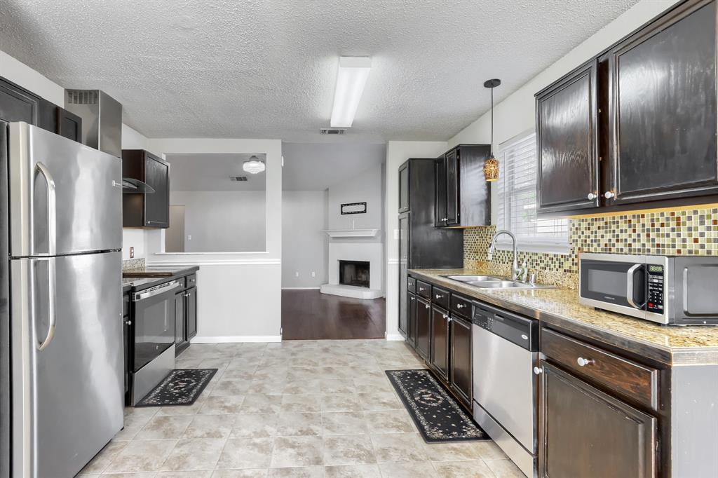 Kitchen featuring dark-finish cabinetry, stone-texture countertops, mosaic tile backsplash, stainless steel appliances, and tile flooring
