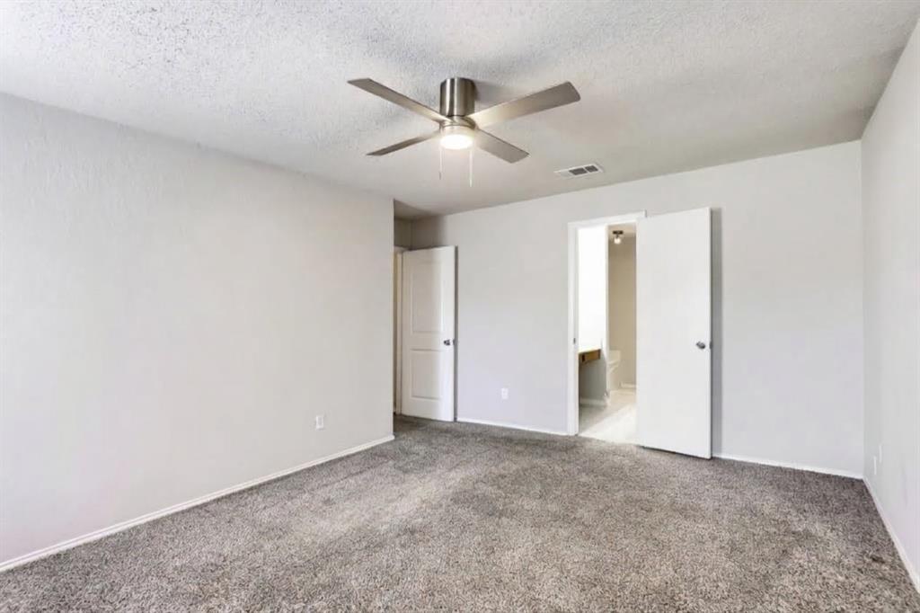 Room featuring neutral-toned carpeting, matte-finish interior walls, and a multi-blade ceiling fan with an integrated light fixture