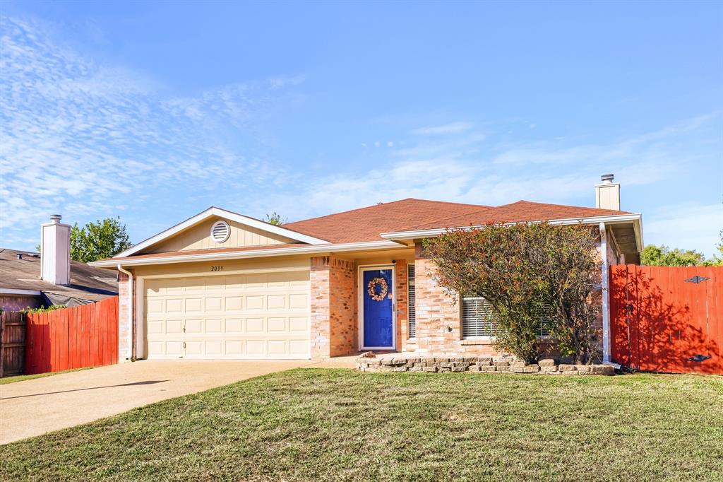 Single-story brick and siding exterior featuring an attached two-car garage, a concrete driveway, and an opaque red perimeter fence