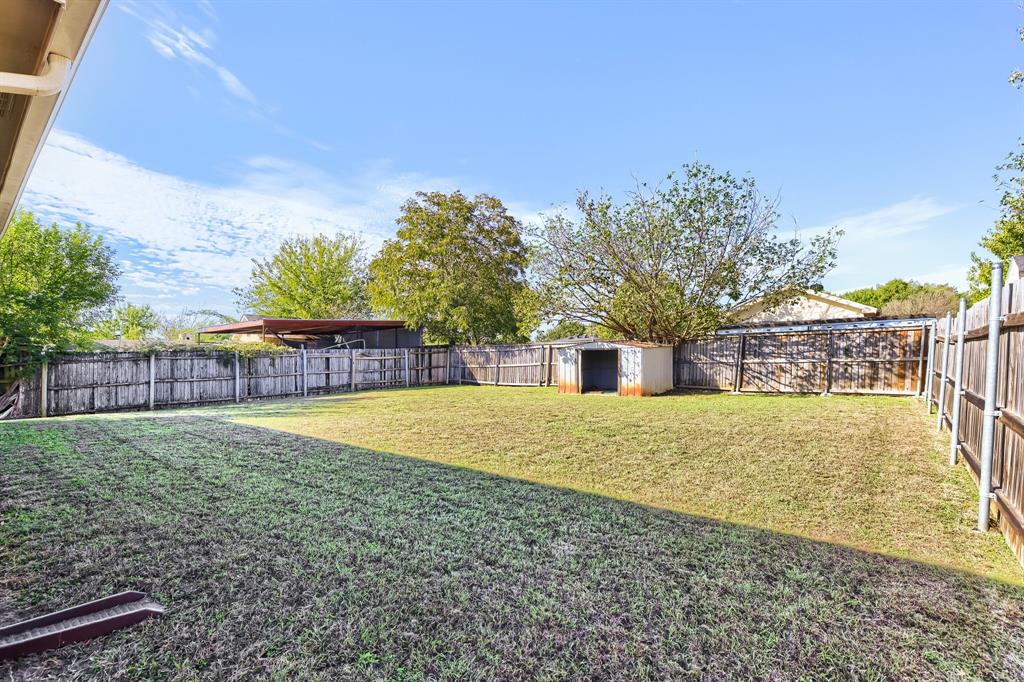 Expansive backyard featuring a lawn, full-perimeter wood fencing, and a detached storage structure
