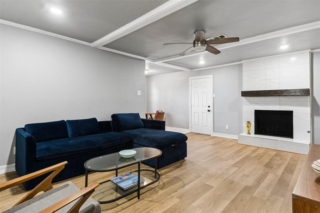 Living area featuring wood-finish flooring, a ceiling with recessed lighting and a central fan, and a fireplace with a white tile surround and a dark wood mantel