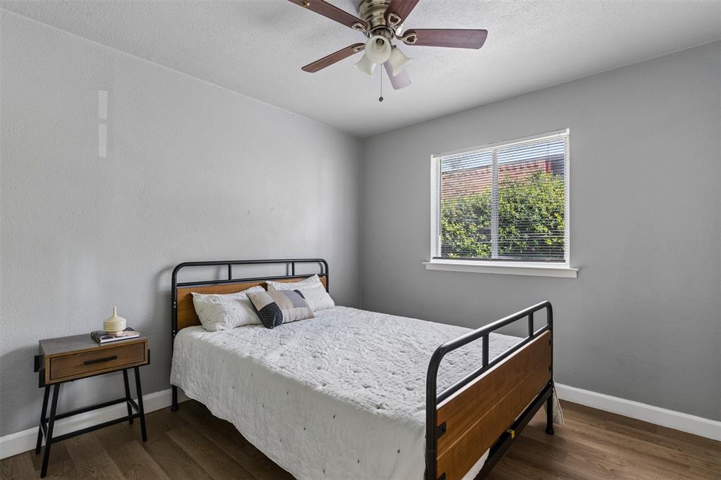 Room featuring neutral-toned walls, wood-finish flooring, a ceiling fan with integrated lighting, and a single-pane window