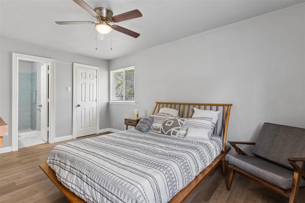 Room featuring wood-finish flooring, a ceiling fan with integrated lighting, and a six-panel interior door