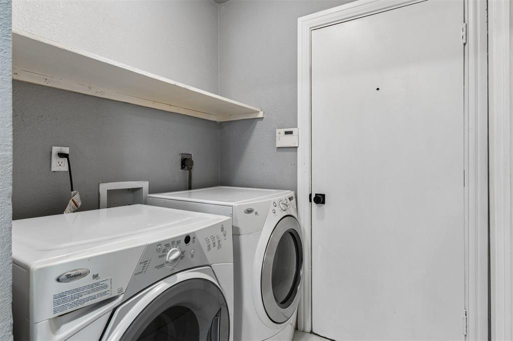 Utility area featuring a wall-mounted shelving unit, dedicated electrical outlets, and a solid-core door with matte black hardware
