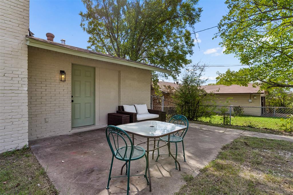Concrete patio with painted brick exterior, covered entryway, and wall-mounted exterior light fixture