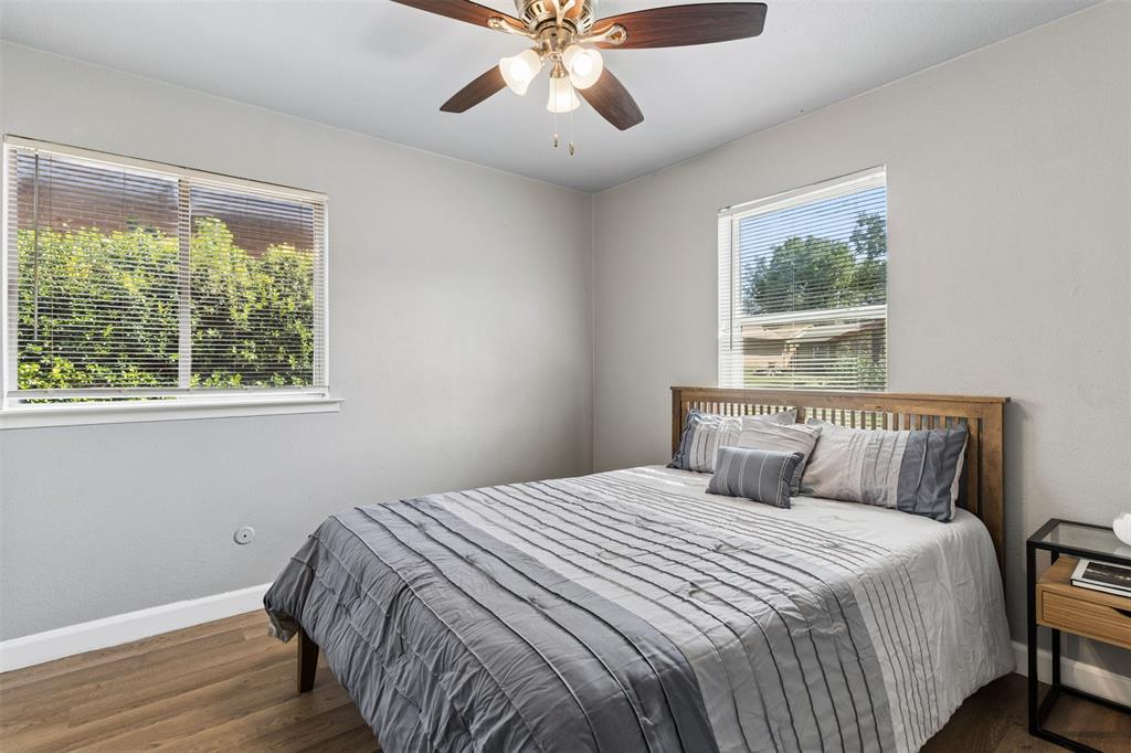 Neutral wall tones featuring wood-finish flooring, dual windows, and a ceiling-mounted fan with integrated light fixtures