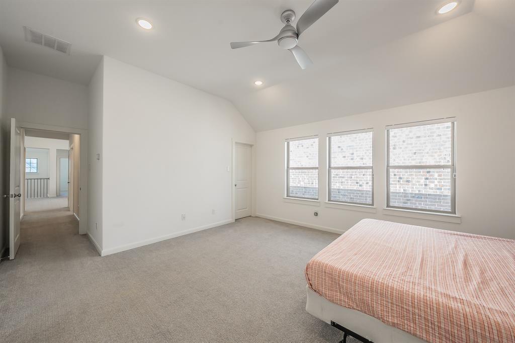 VVaulted ceilings featuring recessed lighting and a brushed-metal ceiling fan, three double-pane windows, and neutral carpeting in the primary bedroom