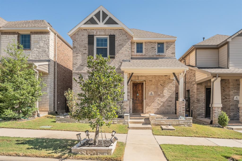 Two-story brick exterior featuring a covered front porch, decorative gable trim, wooden front door, and shuttered windows