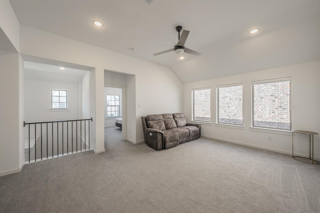 Vaulted ceiling with a ceiling fan, recessed lighting, carpeted flooring, and a metal spindle railing overlooking the lower level, perfect as a game room, secondary living room, or other functional use