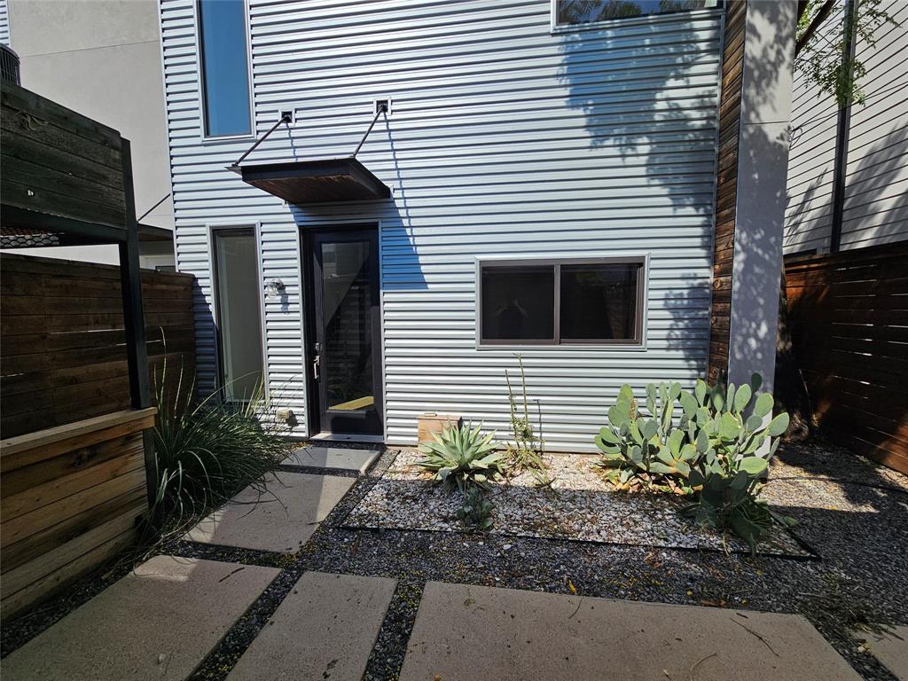 Modern exterior featuring horizontal metal siding, cantilevered steel awning, glass-panel door, and custom paver walkway with stone aggregate borders