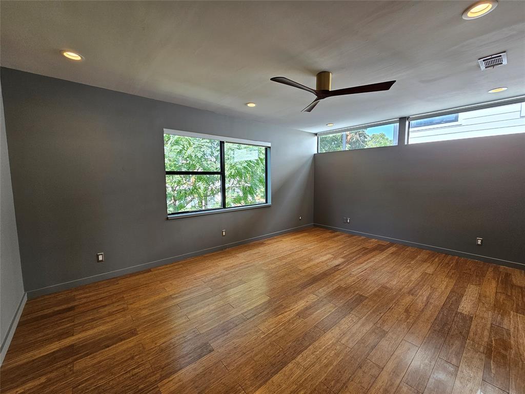 Wood-finish flooring, recessed lighting, ceiling fan with metal finish, horizontal clerestory windows, and dark-toned interior wall paint