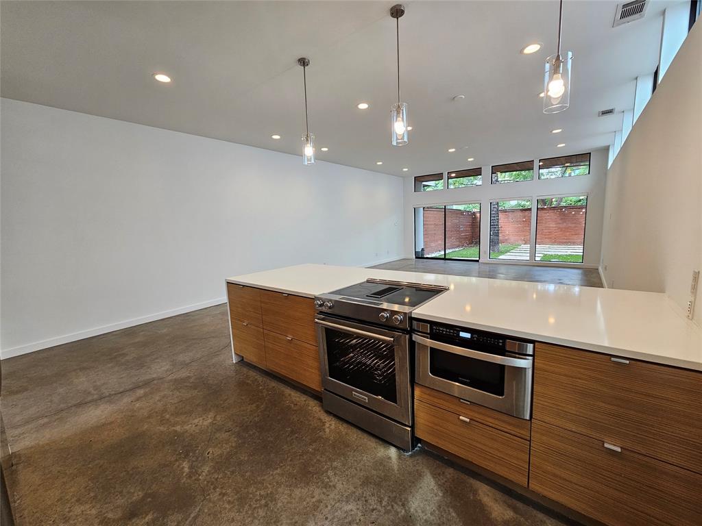 Modern kitchen island featuring wood-finish cabinetry, quartz countertops, a stainless steel range, and a built-in microwave