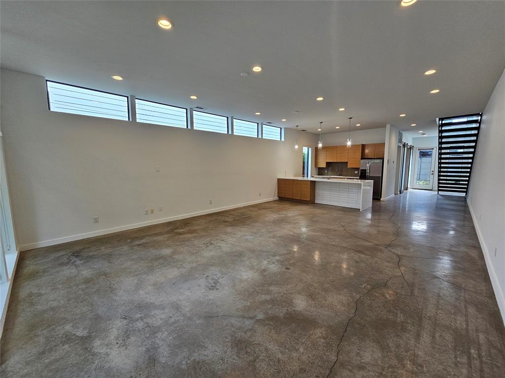 Polished concrete flooring, recessed lighting, horizontal clerestory windows, kitchen featuring built-in cabinetry and an island, and metal staircase