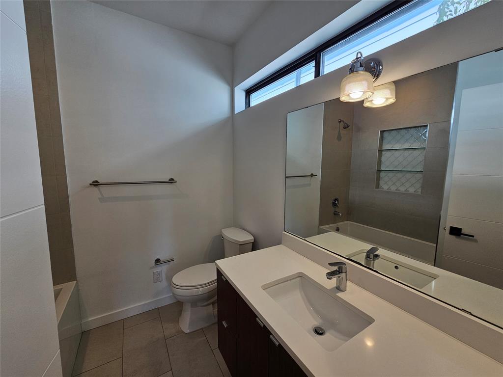 Dark wood-finish vanity with a white countertop and integrated sink, large wall-mounted mirror, transom window, and built-in tiled shower niche