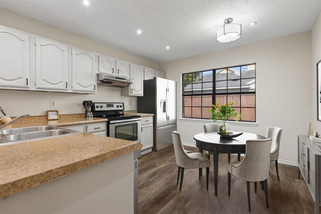 Kitchen featuring white cabinetry, stone-surface countertops, stainless steel appliances, wood-finish flnishing.  *Furniture is virtually staged.