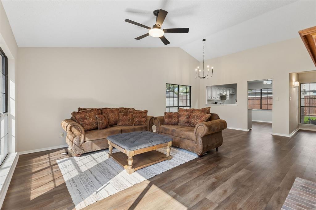 Vaulted ceilings featuring a ceiling fan and a multi-light chandelier, complemented by wood-finish flooring and expansive windows