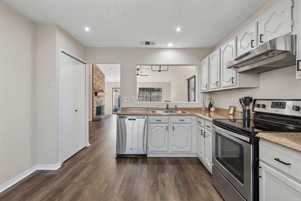 Kitchen featuring white cabinetry, stainless steel appliances, wood-finish flooring, recessed lighting, and a pass-through window