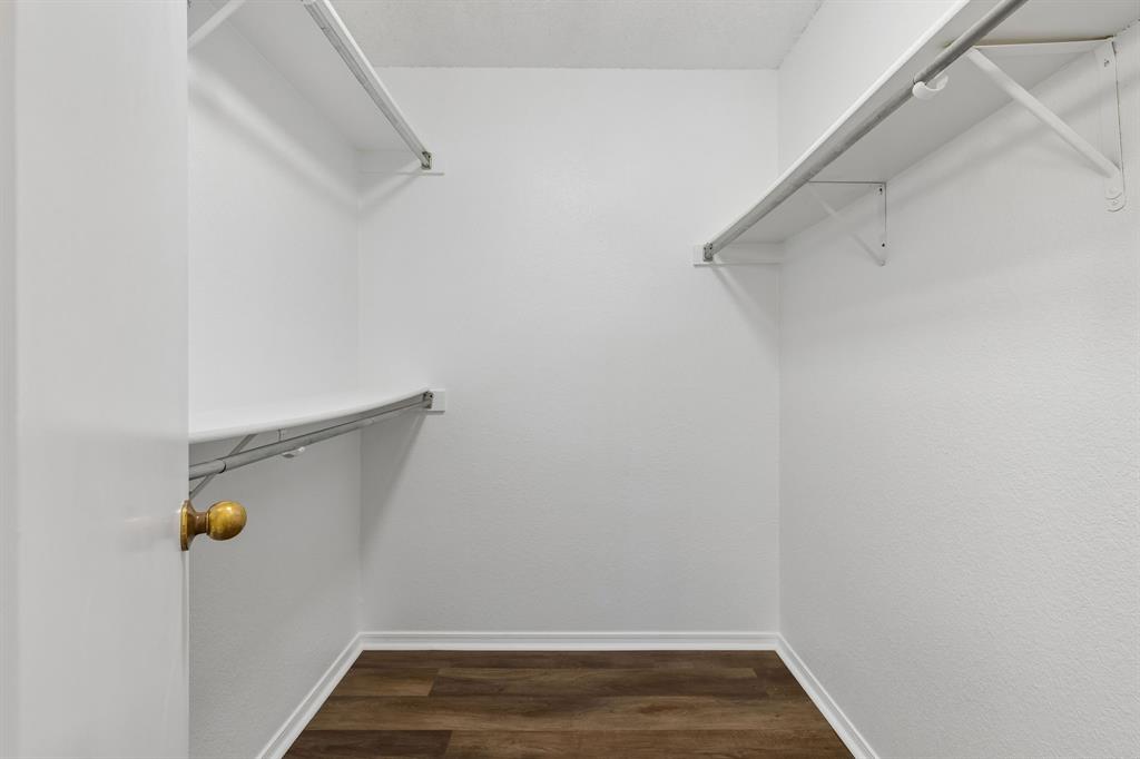 Walk-in closet featuring wood-finish flooring, white walls, and dual-level shelving with integrated clothing rods