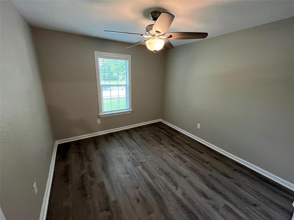 Room featuring wood-finish flooring, neutral wall paint, and a ceiling fan with integrated lighting, centered by a single window with blinds