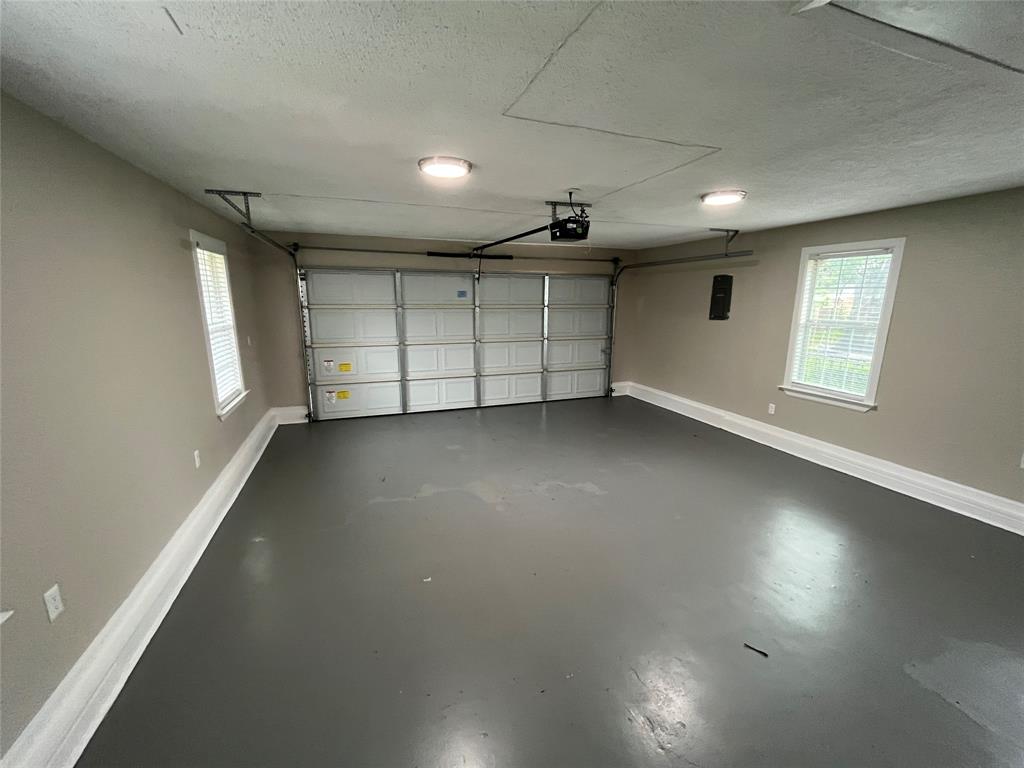 Two-car garage featuring painted concrete flooring, two windows with blinds, and ceiling-mounted lighting