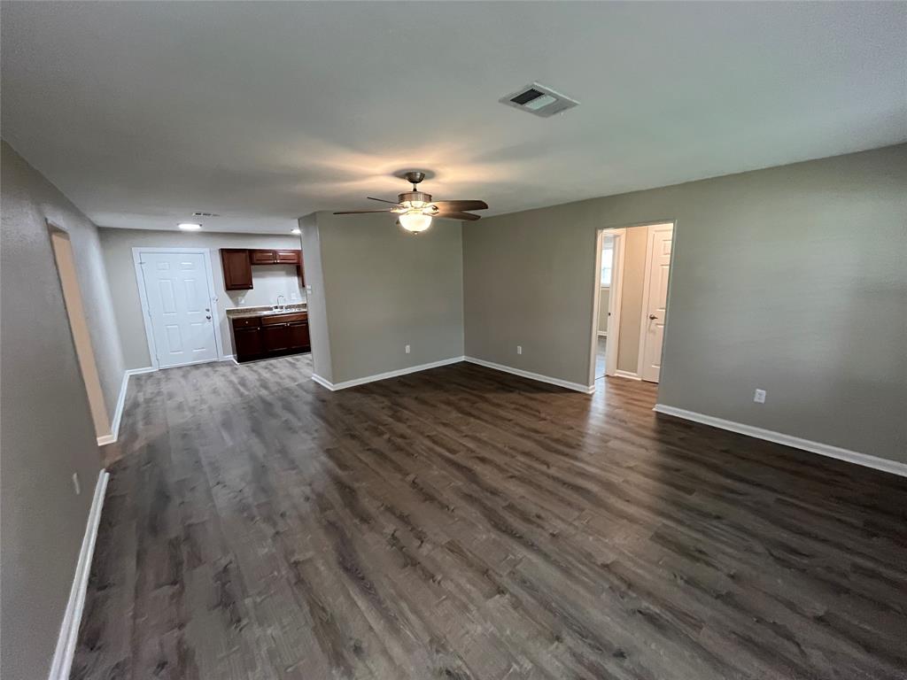 Interior featuring wood-finish flooring, ceiling fan with integrated lighting, and dark-finish cabinetry