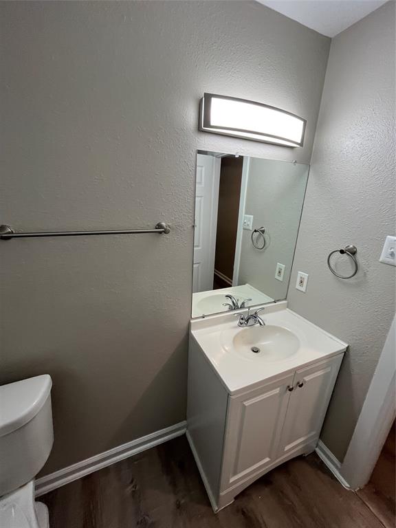 Vanity cabinet with white shaker-style doors, integrated sink, polished metal faucet, rectangular wall-mounted light fixture, and large flat mirror