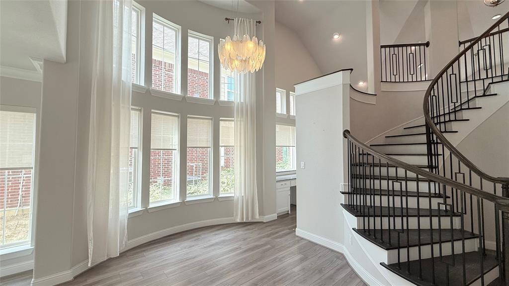 Double-height windows, curved staircase with iron balusters, wood-finish flooring, and built-in desk area Double-height windows, curved staircase with iron balusters, wood-finish flooring, and built-in desk area