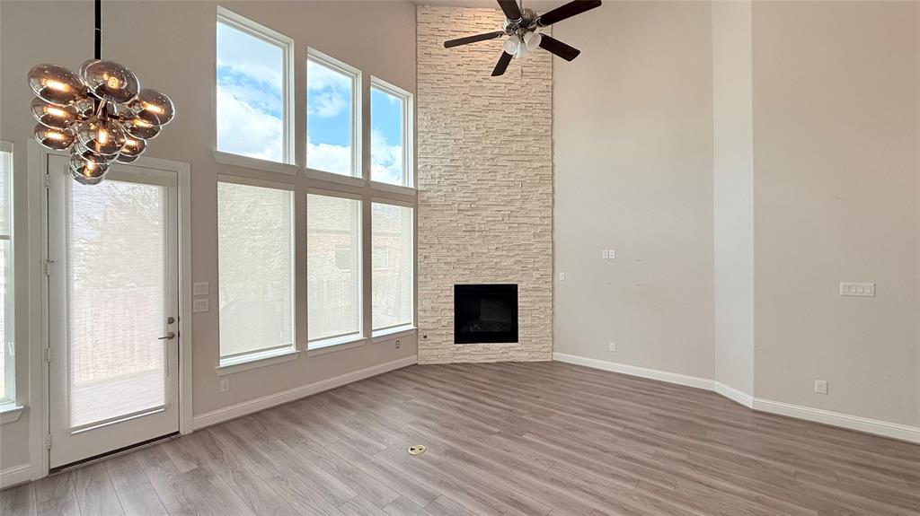 Floor-to-ceiling stone fireplace, soaring vaulted ceilings, wall of multi-pane windows, wood-finish flooring, and multi-globe chandelier Floor-to-ceiling stone fireplace, soaring vaulted ceilings, wall of multi-pane windows, wood-finish flooring, and multi-globe chandelier