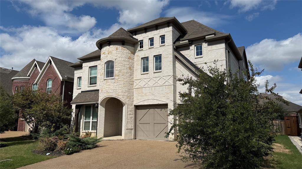 Multi-story exterior featuring light-toned masonry, prominent turret architectural element, multi-gabled roofline, and garage with carriage-style doors Multi-story exterior featuring light-toned masonry, prominent turret architectural element, multi-gabled roofline, and garage with carriage-style doors