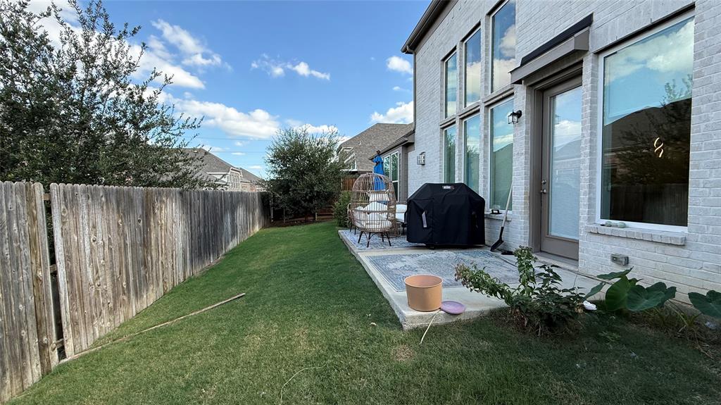 White brick exterior featuring floor-to-ceiling windows, a rear concrete patio, and perimeter wood fencing