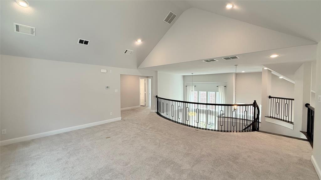 Vaulted ceilings, carpeted flooring, and decorative metal balustrades