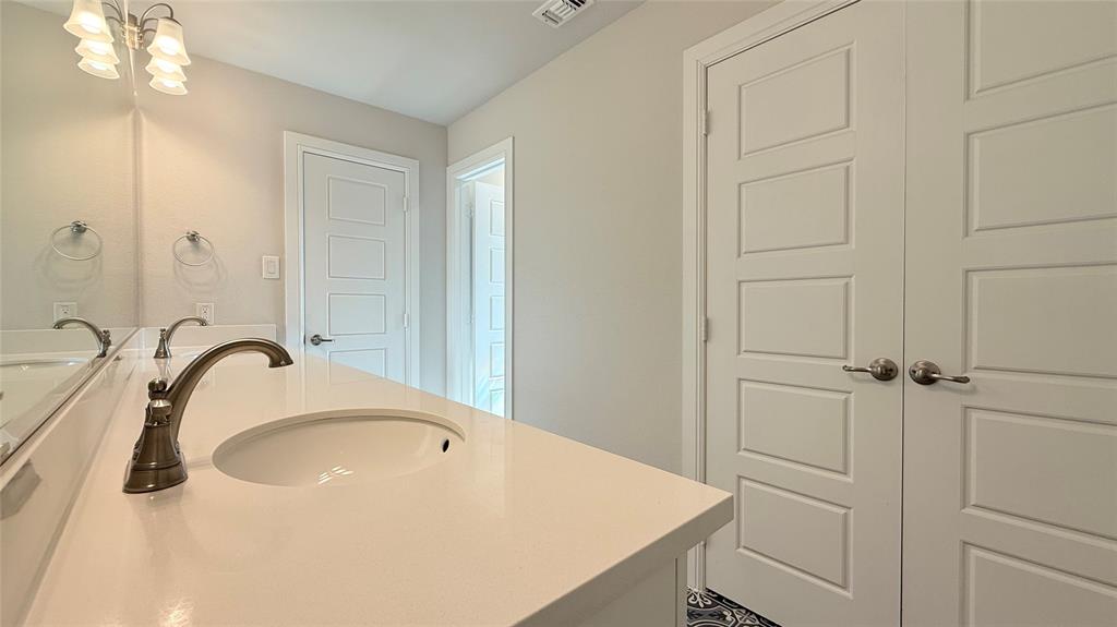 Extended vanity featuring a solid-surface countertop with an integrated oval basin, polished metallic faucet hardware, a multi-bulb vanity light fixture, and classic five-panel interior doors