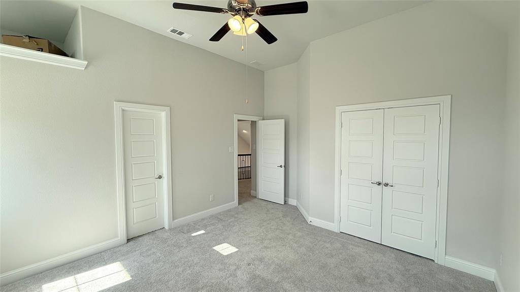 Vaulted ceilings, neutral carpeting, recessed wall niche, ceiling fan with integrated lighting, and white paneled interior doors