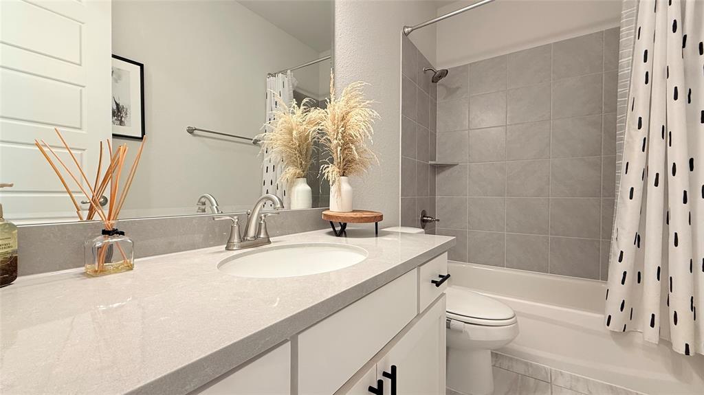 Vanity with a solid-surface countertop, undermount sink, brushed nickel faucet, and shaker-style cabinetry with matte black hardware