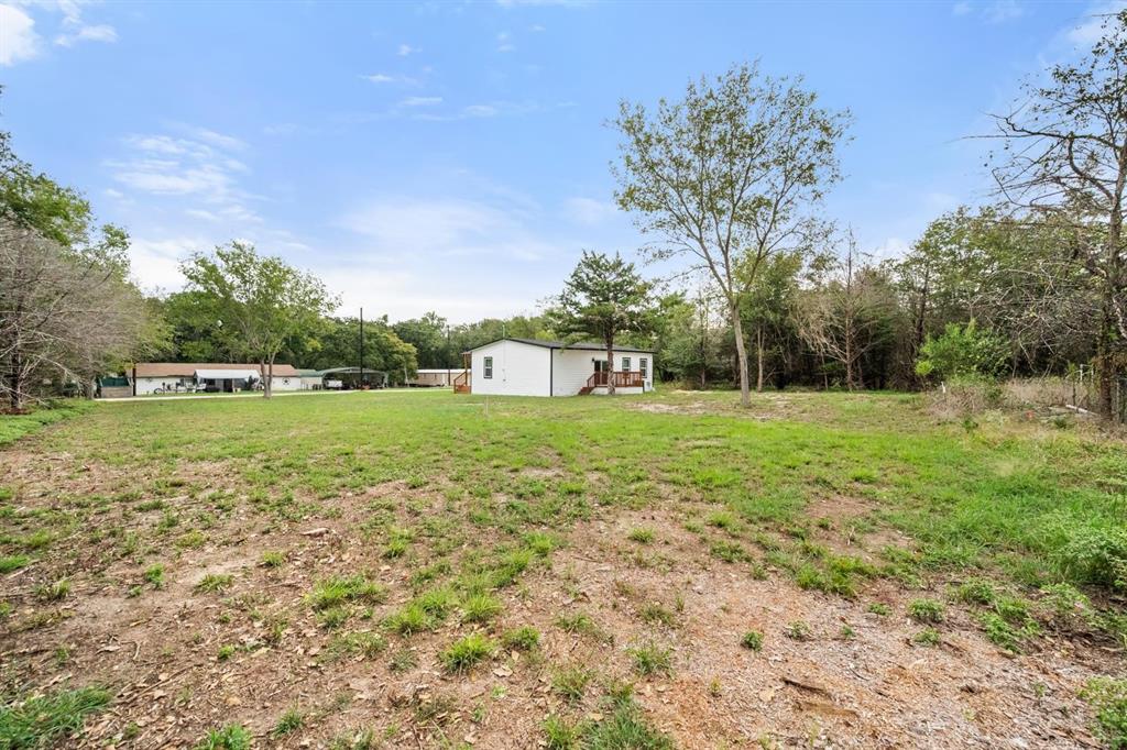 Expansive lot featuring mature trees and a detached wooden deck