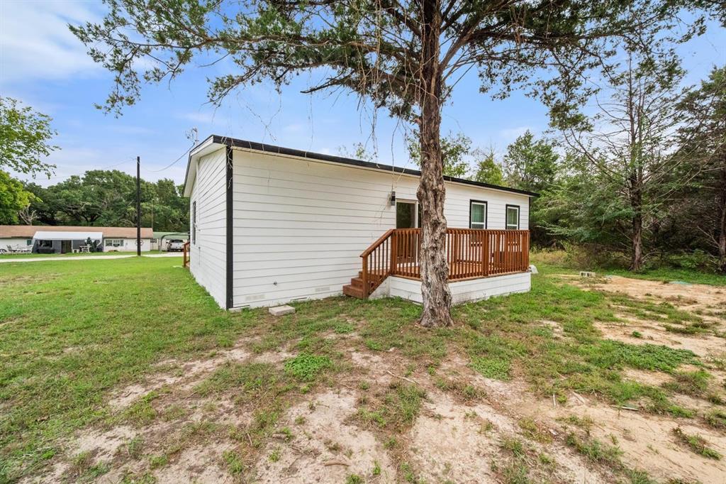 White horizontal siding exterior featuring a stained wood deck with railings and a mature tree