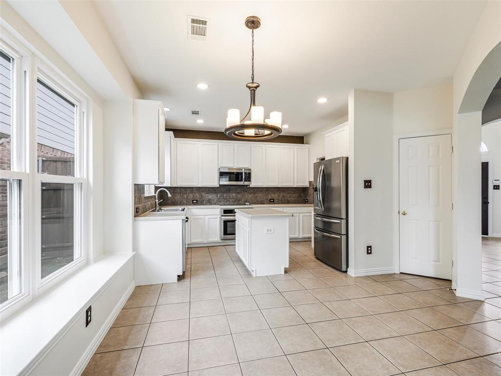 Kitchen featuring white cabinetry, center island, stainless steel appliances, tile backsplash, and tile flooring