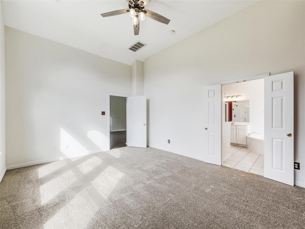 Vaulted ceilings featuring a central multi-blade ceiling fan, wall-to-wall carpeting, and double-door entry