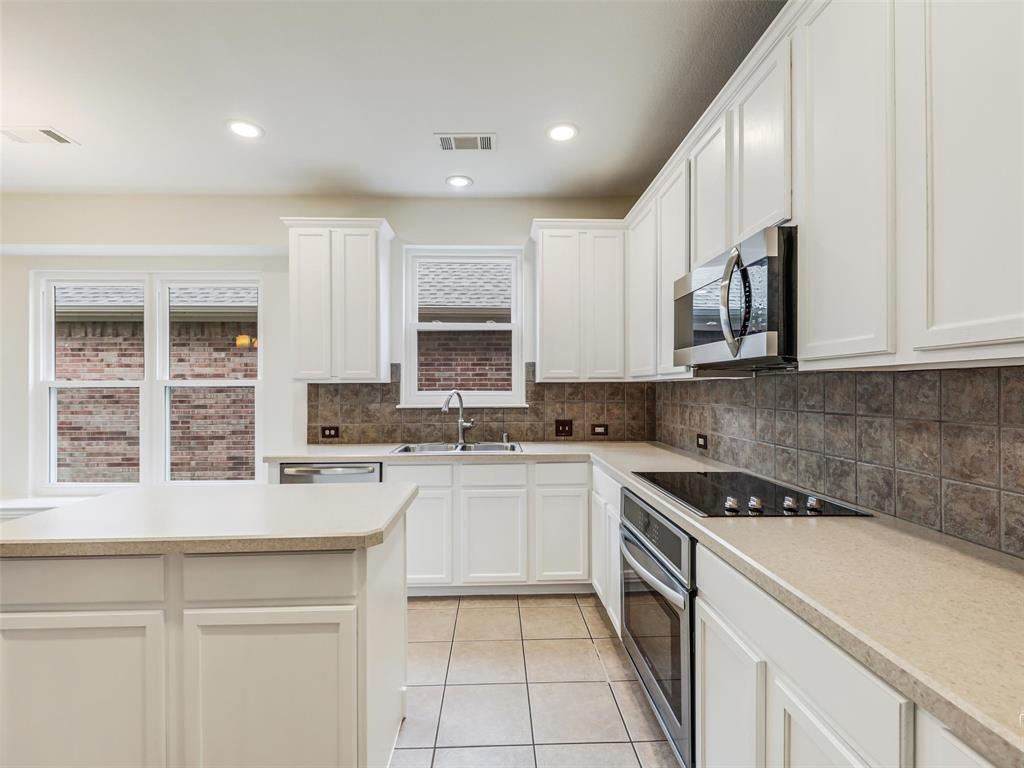 Kitchen featuring white cabinetry, stone-finish countertops, tile backsplash, built-in stainless steel appliances, and tile flooring