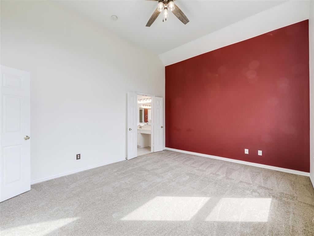 Primary bedroom with vaulted ceilings, carpeted flooring, and a ceiling fan with integrated lighting