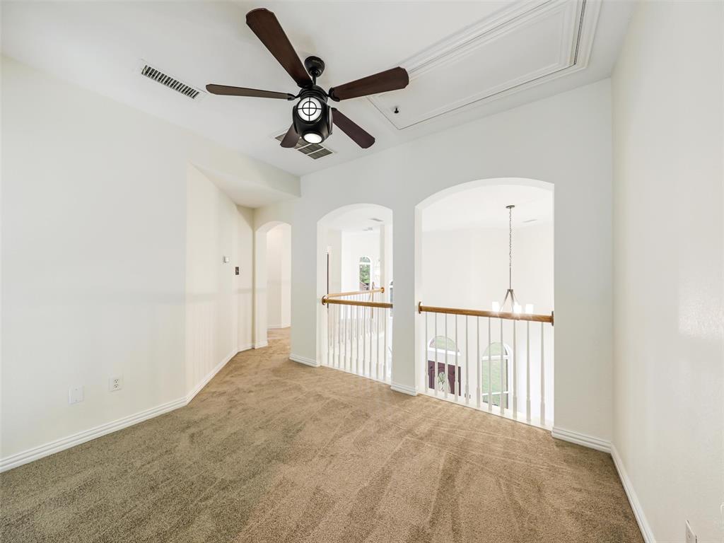 Interior space featuring arched architectural cutouts, a ceiling fan with integrated lighting, and a balustrade railing with a wood-finish handrail