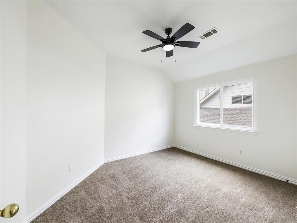 Neutral-toned room featuring a vaulted ceiling, plush wall-to-wall carpeting, and a central ceiling fan with an integrated light fixture