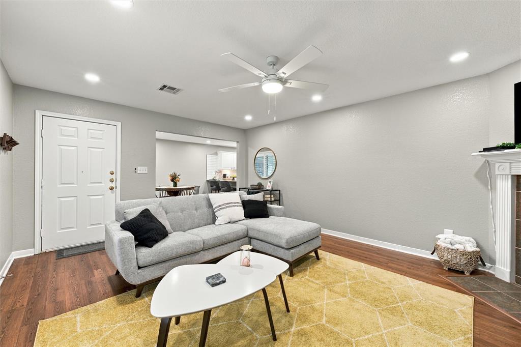 Living area featuring wood-finish flooring, recessed lighting, a ceiling fan with integrated lighting, and a fireplace with a decorative mantel