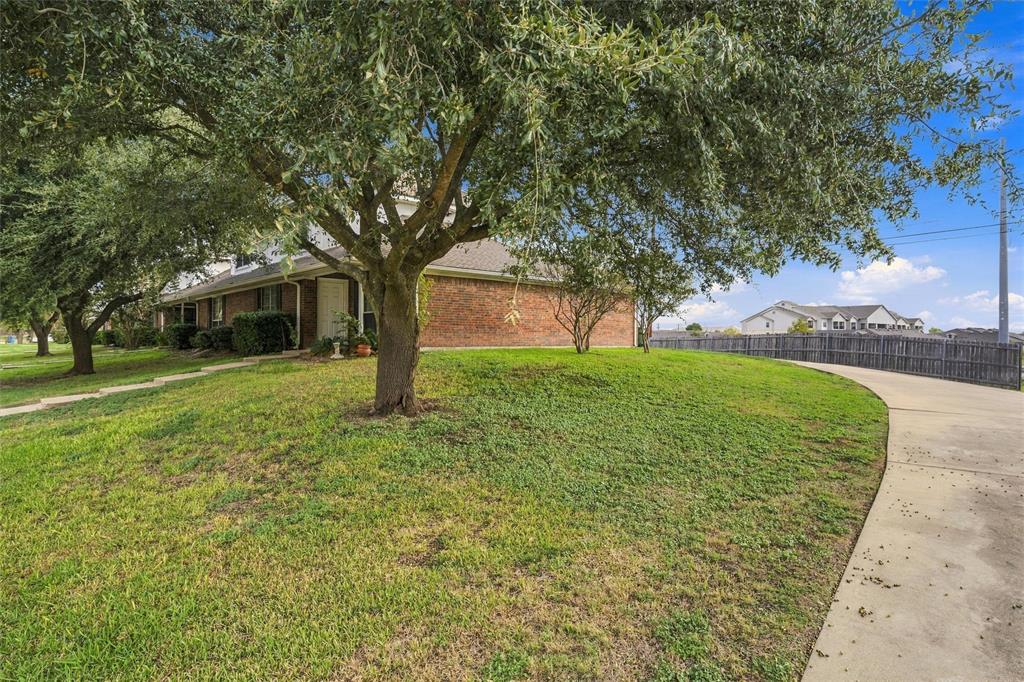 Brick exterior, mature shade trees, expansive grass lawn, and concrete driveway