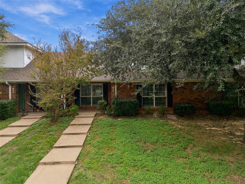 Multi-unit red brick exterior featuring shingle roofing, dark-finished window shutters, and dual concrete walkways leading to separate entrances