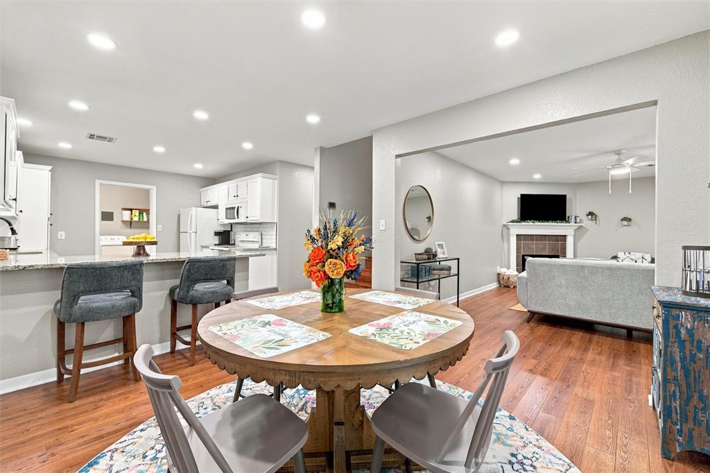 Kitchen featuring stone-finish countertops, white cabinetry, recessed lighting, wood-finish flooring, and a fireplace with a mantel